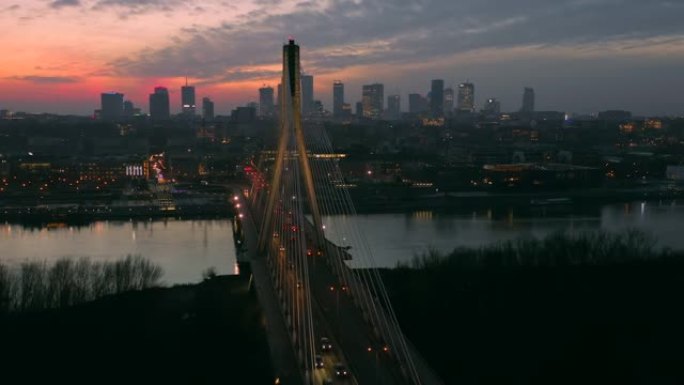 在日落后的黄昏，在华沙市的背景下鸟瞰桥和商业中心的摩天大楼。