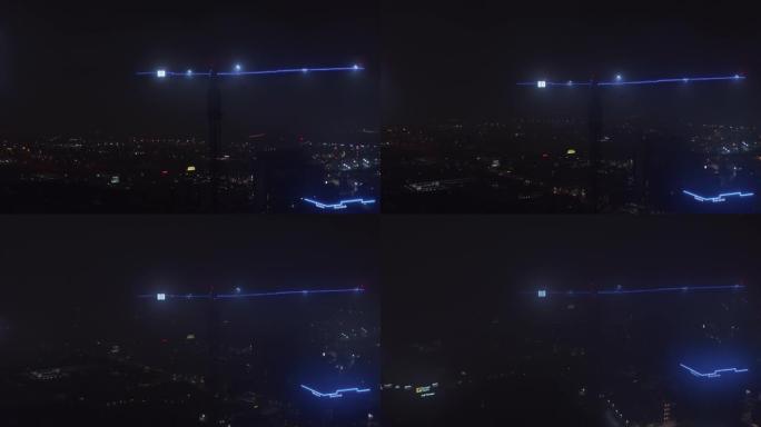 用蓝色霓虹灯和两个大字母B照明的建筑起重机臂。背景为灯光的夜晚城市景观。无人机的鸟瞰图。美国德克萨斯