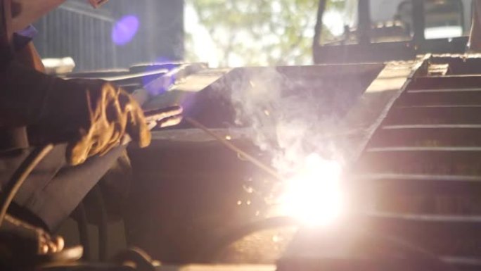 工业工厂机械工人曼钢焊工在工业工厂戴焊接面罩焊钢。