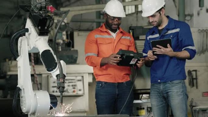 男性工程师和黑人非洲工程师在自动化工厂与工业机器人一起编程。
