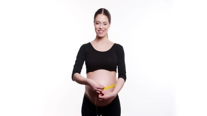 怀孕的白人年轻女子的美丽身体使用卷尺检查白色工作室背景下的婴儿发育，医疗保健和健康。健康腹部健康怀孕