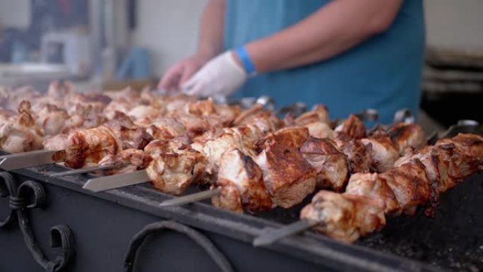 厨师在金属串上的美食广场上的开放式烤架上烹饪多汁的猪肉烤肉串