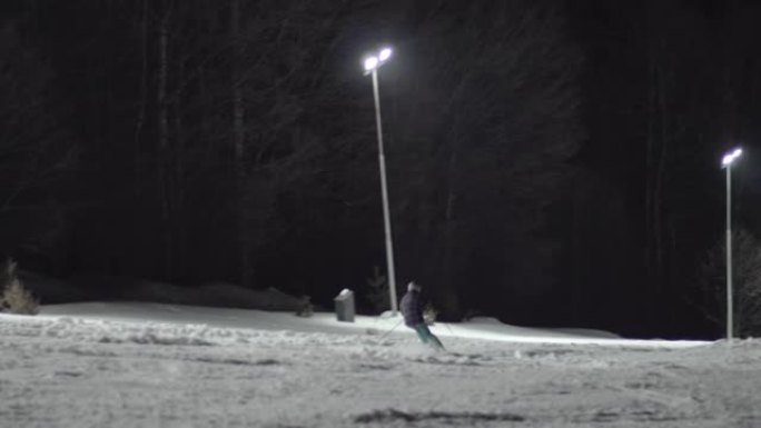 在夜间照明的斜坡上雕刻的滑雪者制作技巧的散焦镜头，选择性聚焦