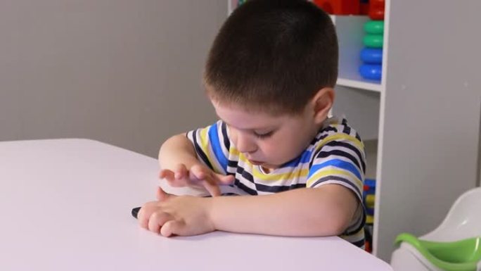 一个3-4岁的小男孩看着手机屏幕。