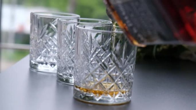 酒保将威士忌，白兰地，白兰地从瓶子里倒入玻璃杯中。