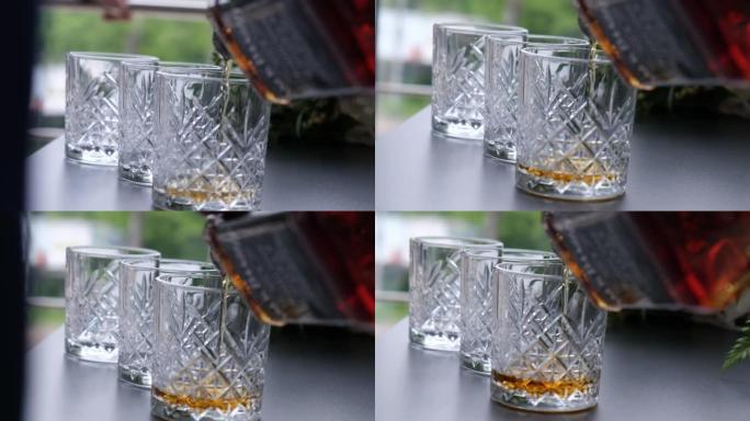 酒保将威士忌，白兰地，白兰地从瓶子里倒入玻璃杯中。