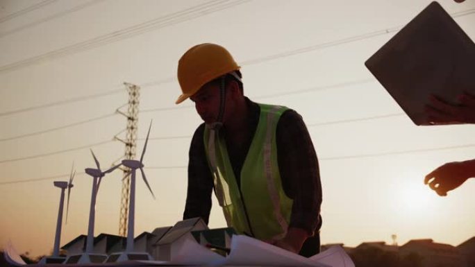 亚洲工程师，领班或领导者讨论建筑工地项目中的家用太阳能电池农场和风力涡轮机模型