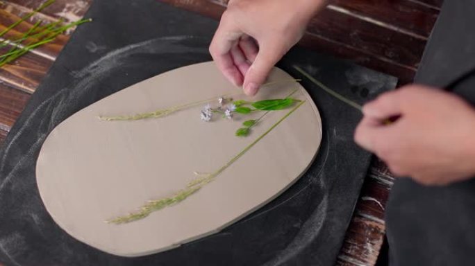 陶工把叶子印在粘土板上。在陶器工作室制作手工陶器。特写，慢动作