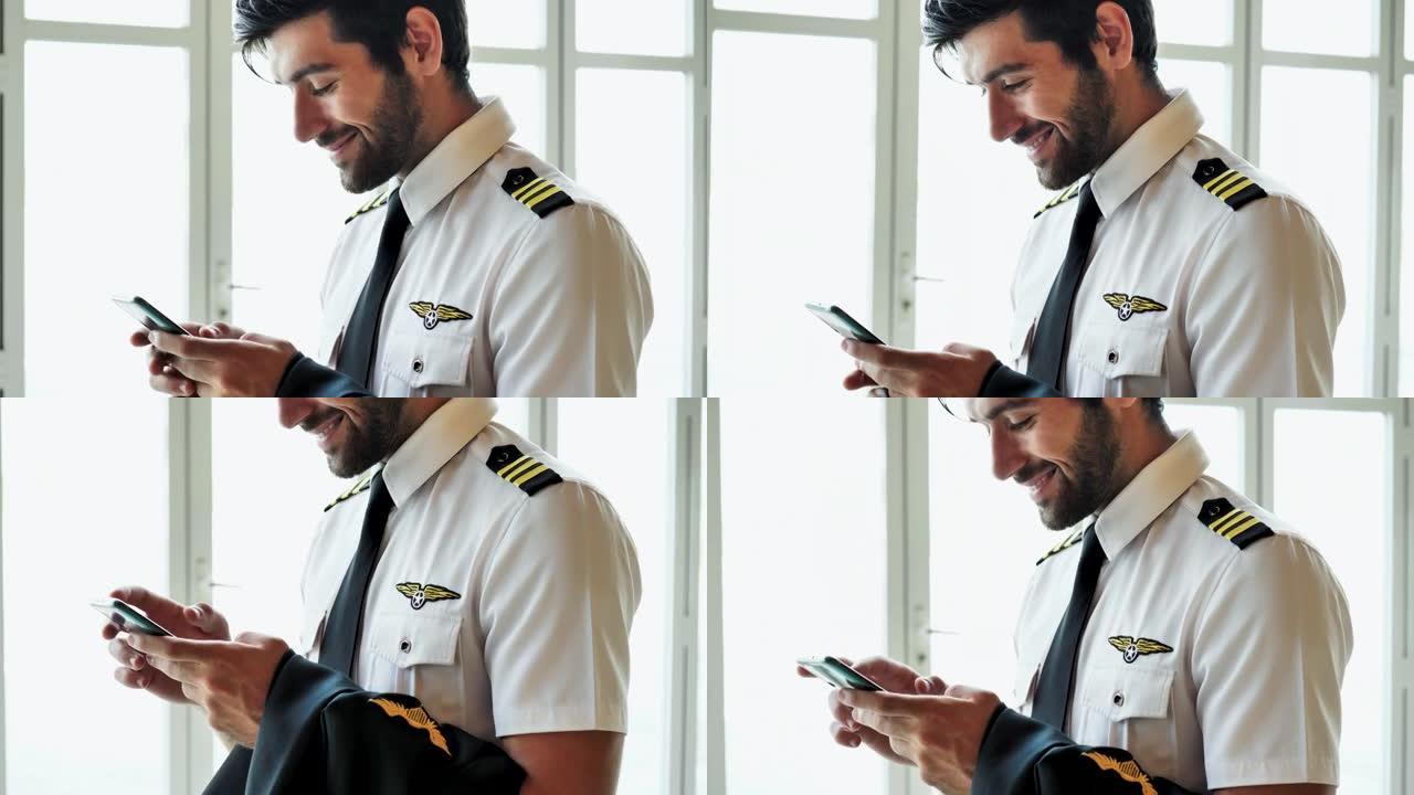 飞行员在使用手机时走在机场的走廊上。