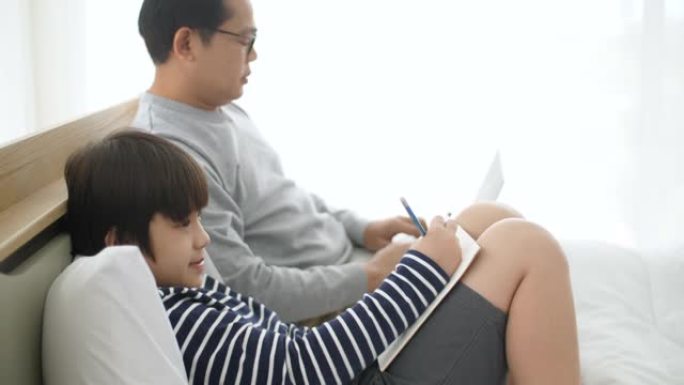 单身父亲在笔记本电脑上工作时帮助儿子做作业