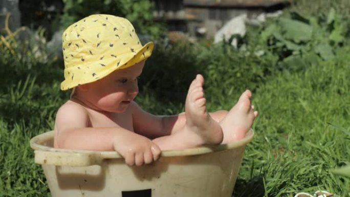 夏天，婴儿在阳光明媚的日子里在房子院子里的街道上休息，洗澡，在骨盆里游泳。慢动作