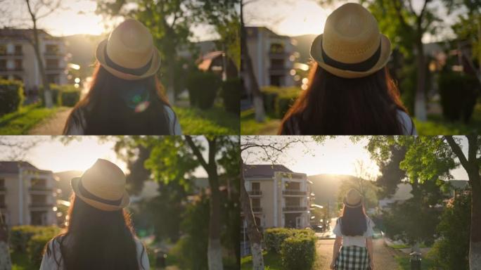 夏天。戴草帽的女人，向前走。后视图。背景中的日落。多莉开枪