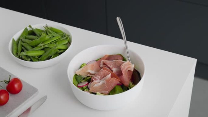 新鲜沙拉配菠菜、西兰花、萝卜和意大利熏火腿。健康食品概念 -- 定格动画