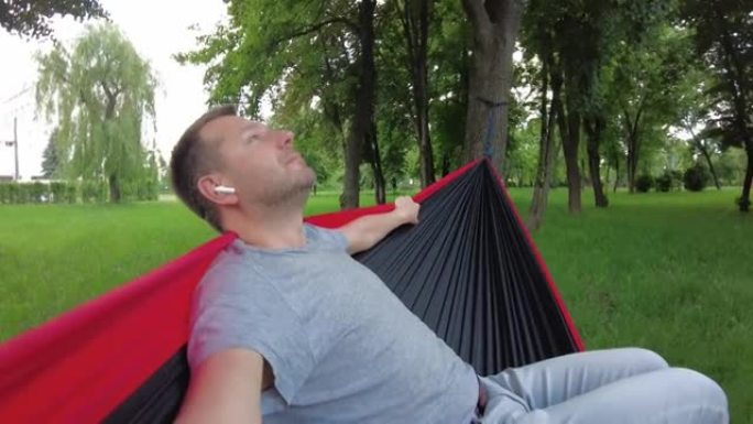 一个男人在吊床上享受夏日的大自然。