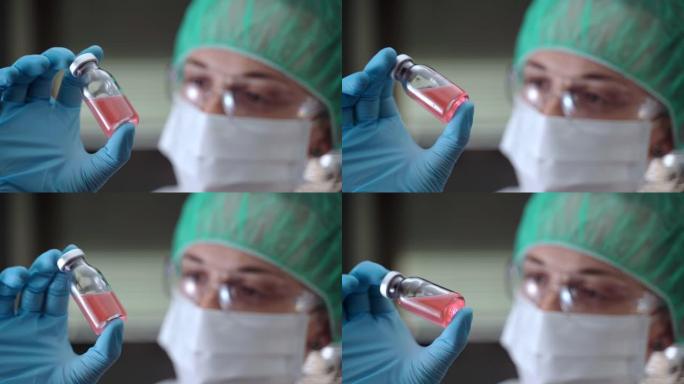 科学研究人员手中的红色溶液无菌小瓶的特写镜头。保护罩中的化学家持有潜在的抗新型冠状病毒肺炎疫苗安瓿。
