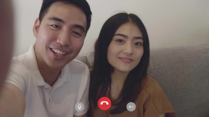 亚洲夫妇在社交媒体上与朋友视频通话，同时在冠状病毒大流行期间在家中自我隔离。