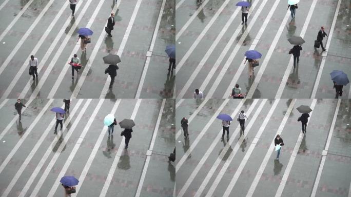 一群面目全非的人在雨中戴着五颜六色的雨伞走在车站广场上。慢动作。雨季。
