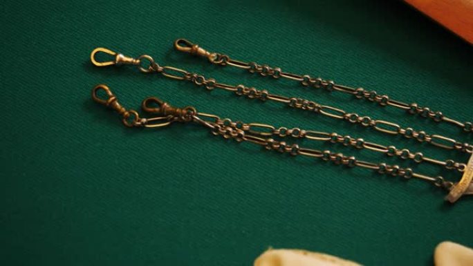 带链条的豪华金色古代吊坠。库存镜头。绿色织物背景上的老式复古珠宝特写。