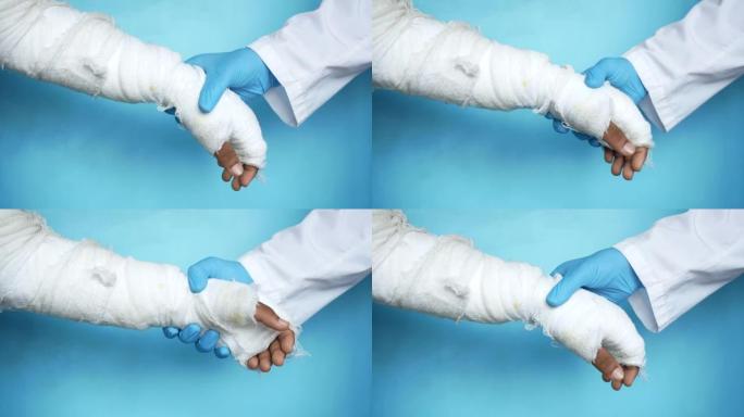 医生手戴手套用绷带握住受伤的疼痛手