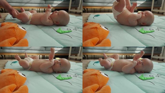 可爱的男婴躺在婴儿活动健身房玩垫子和他的父亲玩耍，婴儿感官发育，3个月大的新生婴儿在客厅地板上