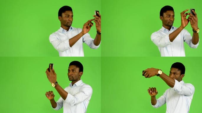 年轻英俊的黑人用智能手机拍摄照片 -- 绿屏工作室