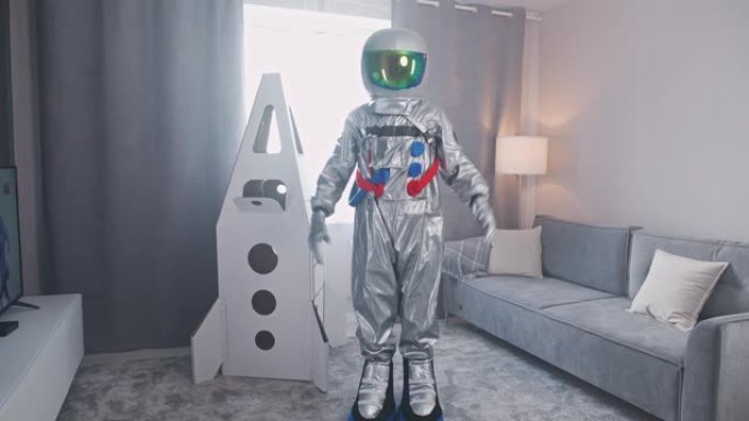 穿着太空服的中年男子站在客厅里，旁边是航天飞机的纸板模型，宇航员戴上头盔，一个孩子的梦想，4k慢动作