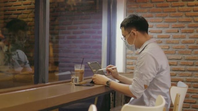 带防护面罩的自由设计师创造了一些新的想法，并在咖啡店的智能平板电脑中勾勒出它-股票视频