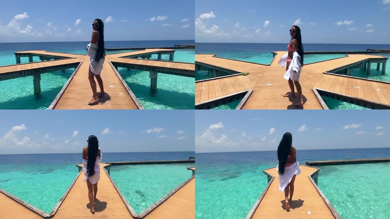 4K视频:亚洲女人走在码头上，在马尔代夫度过暑假，享受阳光