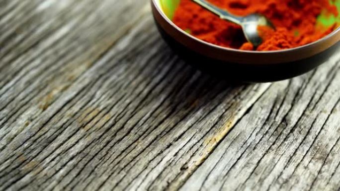 木质背景上的一碗磨碎辣椒