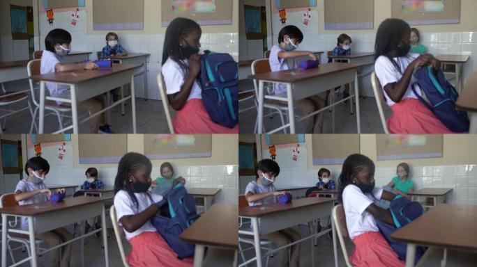 学生戴着口罩，在教室里从背包里拿出教材。新型冠状病毒肺炎概念