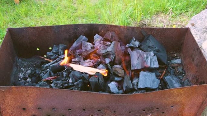 一个人的手点燃了烤架上的煤