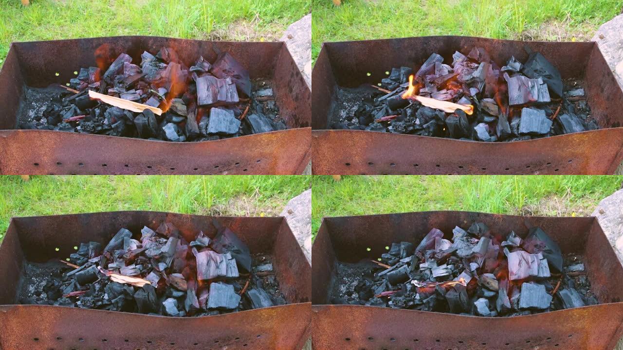 一个人的手点燃了烤架上的煤