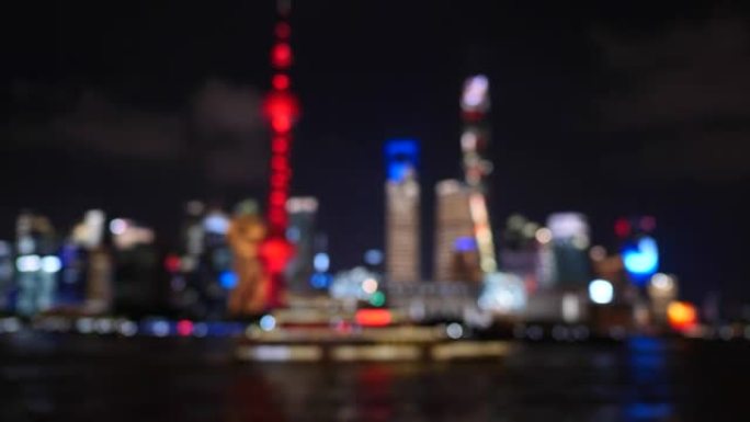 夜间散焦的上海市容4k镜头，以上海地标背景在黄浦江航行的观光旅游船，4k b滚动镜头。