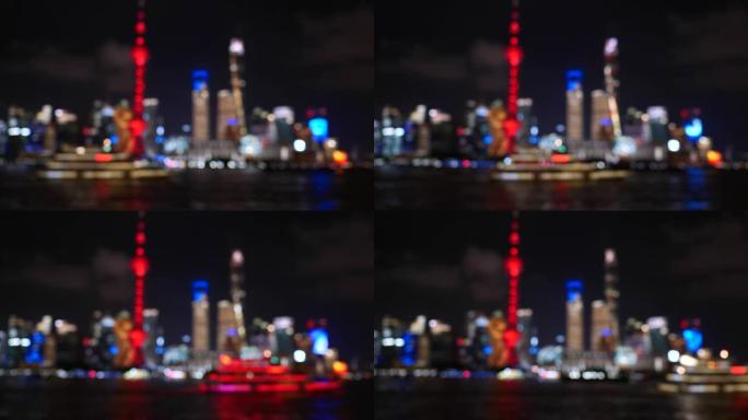 夜间散焦的上海市容4k镜头，以上海地标背景在黄浦江航行的观光旅游船，4k b滚动镜头。