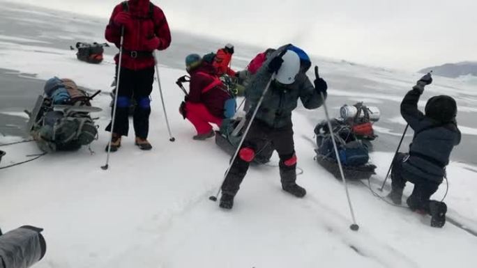 一群游客站起来，试图抵抗在冬季徒步旅行中将他们吹走的强风