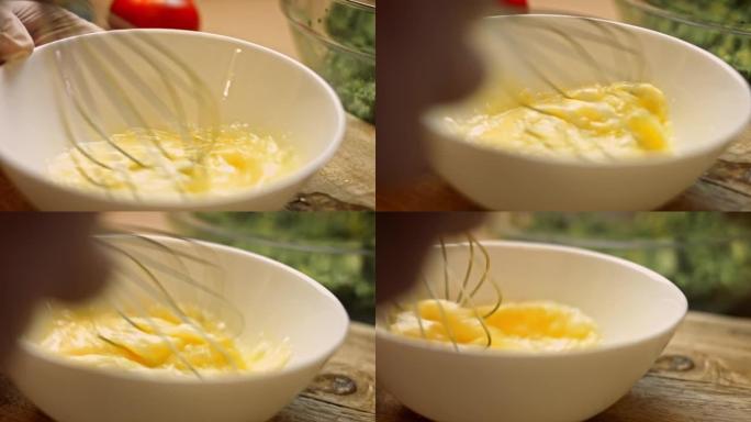 用金属碗中的厨房打蛋器关闭打蛋器，用于早晨的煎蛋或炒鸡蛋。在面包店煮搅拌鸡蛋以准备面团。烹饪早餐概念