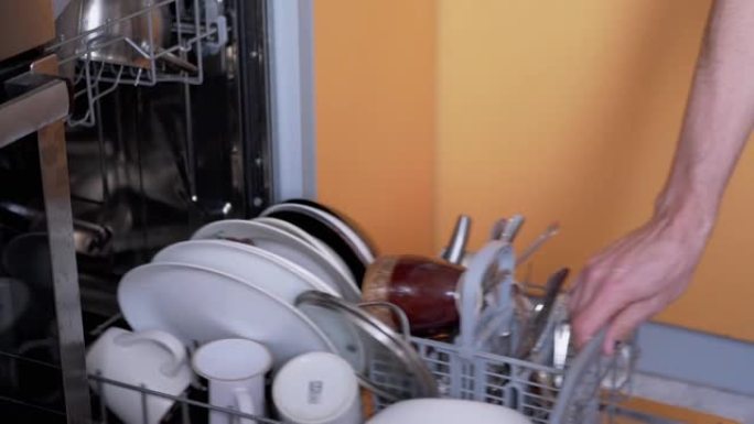 人类将未洗过的脏盘子放在洗碗机的架子上。缩放
