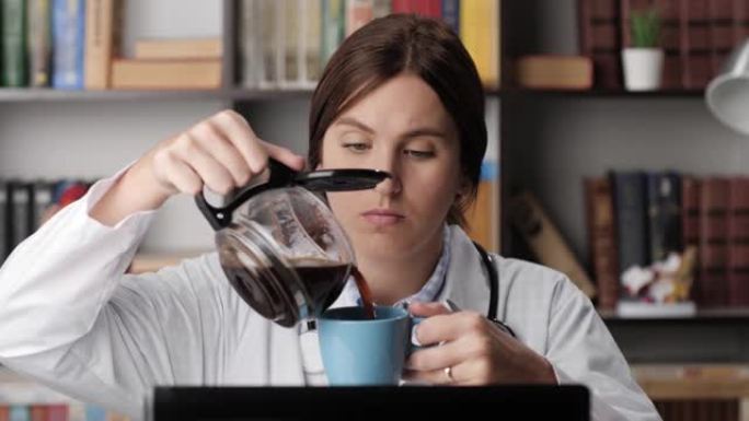 电脑上累了的医生倒酒喝咖啡。办公室工作场所穿着白大褂的女医生在电脑上工作时，将咖啡机中的咖啡倒入蓝色