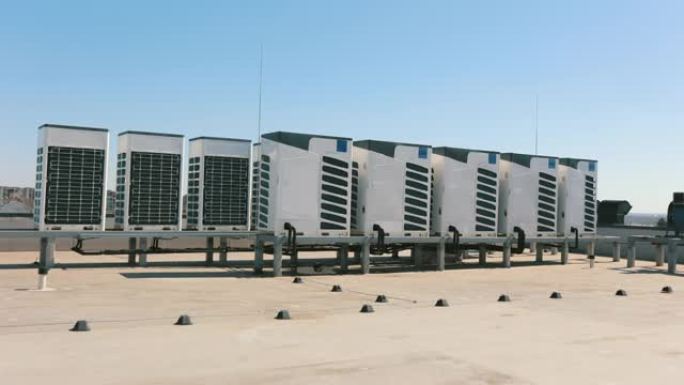 两排空调的空调系统位于商务中心的屋顶上。将相机从左向右移动。阳光明媚。4K