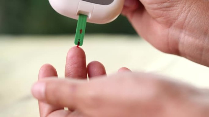 使用柳叶刀笔和血糖仪在手指上检查血糖水平，关闭糖尿病测试。世界糖尿病日的概念，血糖，高血糖，胰岛素，