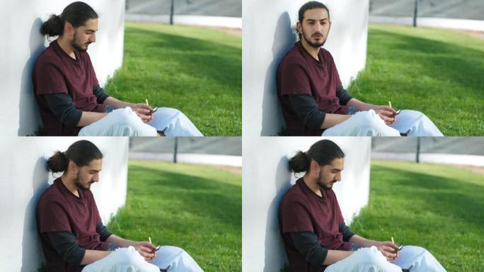 年轻迷人的阿拉伯男子坐在公园里，使用智能手机