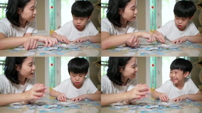 亚洲家庭，母子躺在地板上做拼图游戏。女人拍手，男孩微笑。在家工作期间家庭幸福。女人教孩子解谜。开朗的