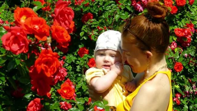 一个年轻女人抱着一个婴儿在玫瑰花园里