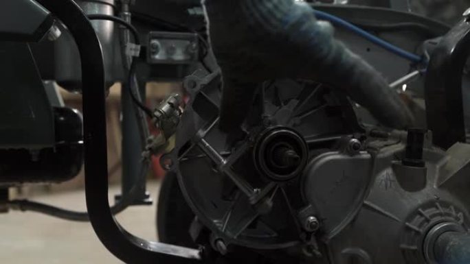 汽车车间的机械师拆卸三轮车发动机中的变速箱
