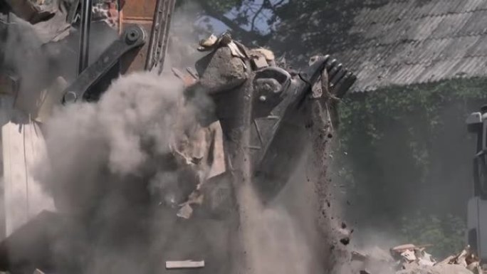 挖掘机铲斗将被摧毁的建筑物中的垃圾和杂物装载到卡车中。