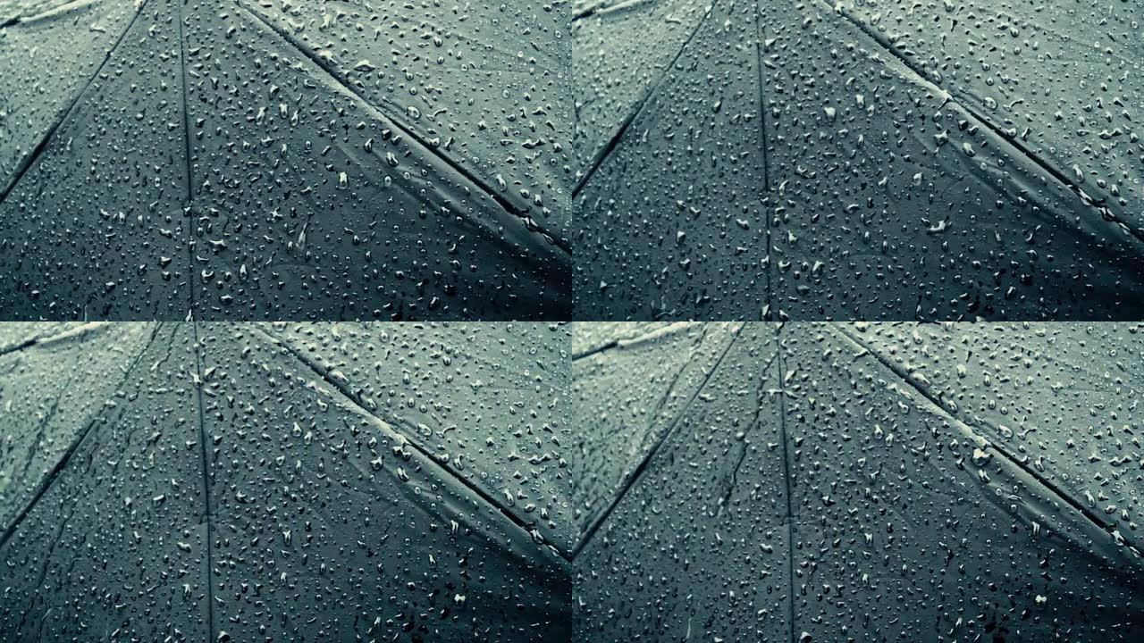 黑色雨伞上的雨滴。极端特写。雨滴落在阳伞上。抽象纹理模式。雨季自然背景镜头。选择性聚焦。浅景深。复制