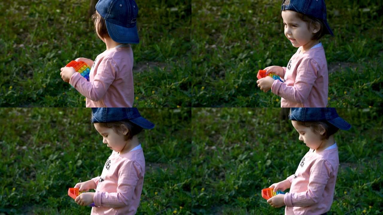 一个孩子带着流行的感官玩具在街上玩耍。女孩按下五颜六色的彩虹柔软的硅胶气泡。缓解压力和焦虑。时尚坐立