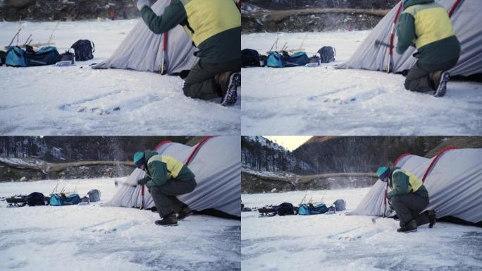 该男子用斧头在冰上打了一个洞，水将从帐篷解冻的底部排出