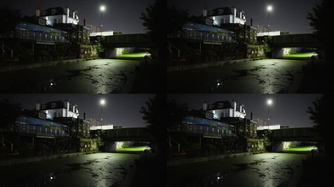 运河和建筑物的喜怒无常的夜景，水上有明亮的绿藻