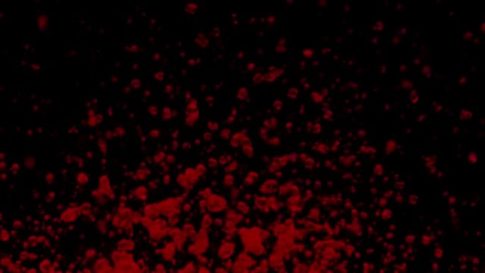 红色水滴飞起来，在黑色背景上向不同方向喷射。透明液体的宏观拍摄产生由声音振动引起的液滴和飞溅。慢动作